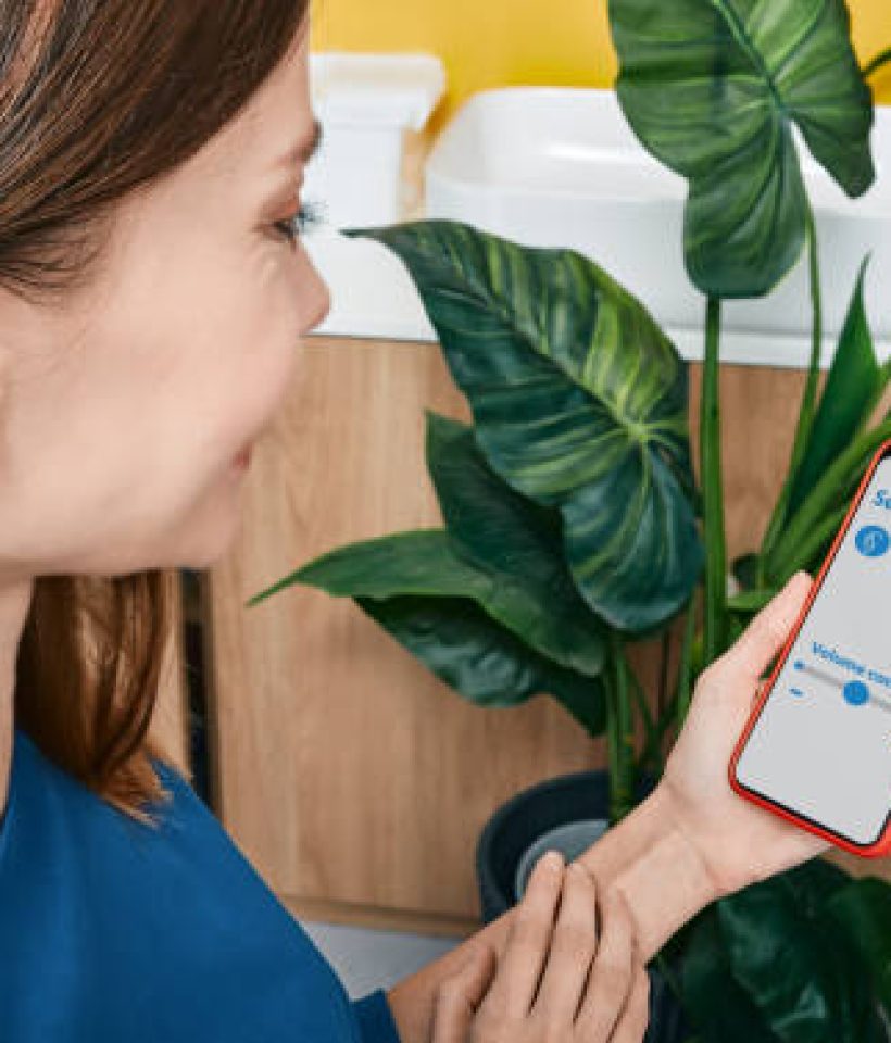 IMG_5157 Hearing impaired woman adjusts settings for her BTE hearing aid via smartphone. Hearing aids, deafness treatment, innovative technologies at audiology