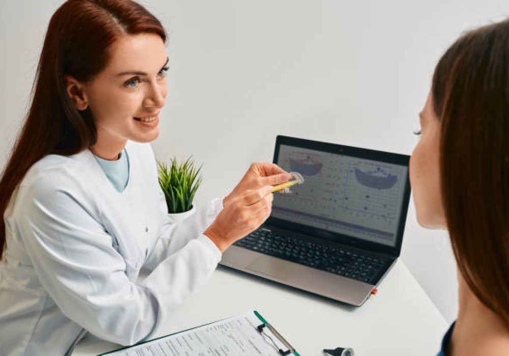IMG_5162 Audiologist advising patient to use BTE hearing aids to treat her deafness during consultation at hearing clinic. Audiology, hearing solutions