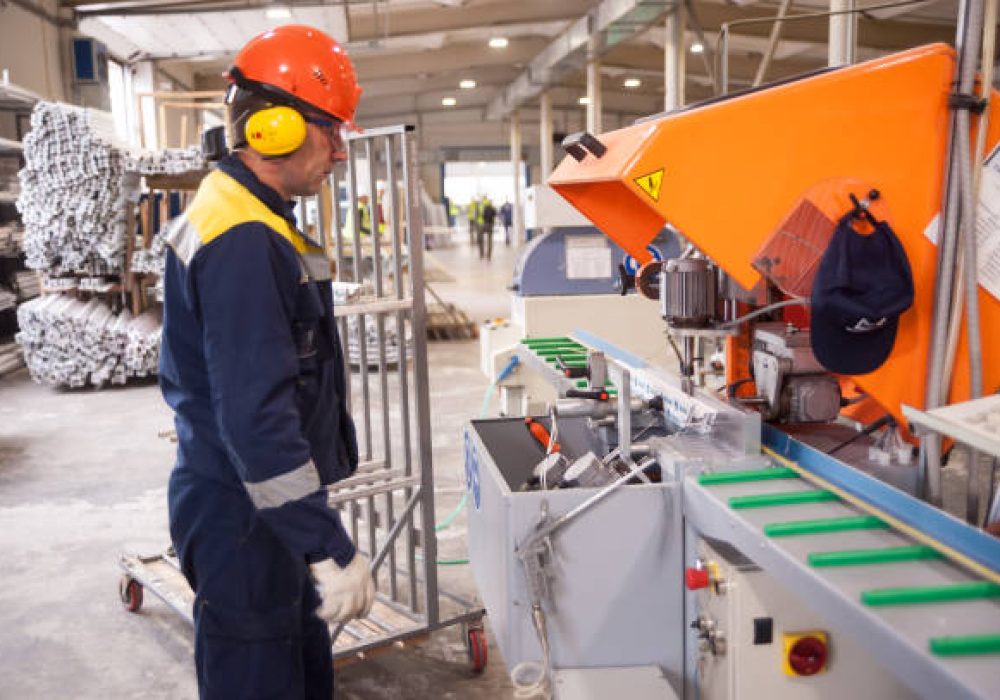 Tyumen, Russia - November 30, 2017: Workshop of Mostootryad-36 Factory. Plastic window and door manufacturing. Worker cutting PVC profile